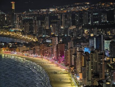 Canlı kentsel ufuk çizgisi sakin suları renkli yansımalar ve canlı atmosferle aydınlatıyor.