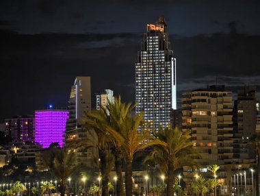 Canlı kentsel ufuk çizgisi sakin suları renkli yansımalar ve canlı atmosferle aydınlatıyor.