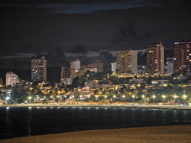 Canlı kentsel ufuk çizgisi sakin suları renkli yansımalar ve canlı atmosferle aydınlatıyor.