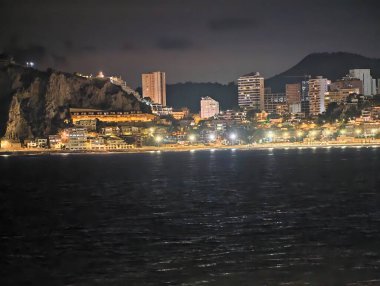 Huzurlu bir gece limanı, sakin bir sahil kenti uzak ufuk çizgisi yansımaları ve sakin bir su.