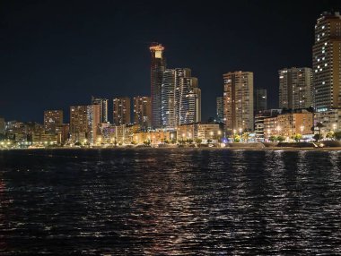 Canlı kentsel ufuk çizgisi sakin suları renkli yansımalar ve canlı yansımalarla aydınlatıyor 