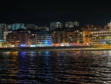 Gece şehir ışıkları canlı yansıyor, dinamik şehir kıyısı geceleri canlı görüntülerle dolup taşıyor.