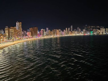 Alacakaranlık kıyı şeridi şehir aydınlatmasını ve editoryal görüntüler için dokulu suyu vurguluyor