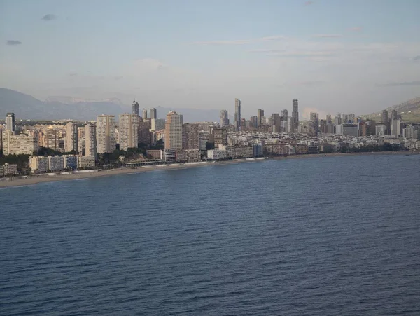 Ufuk çizgisi olan parlak deniz önü, uzak dağları ve canlı mimarisi olan parlak şehir kıyısı.