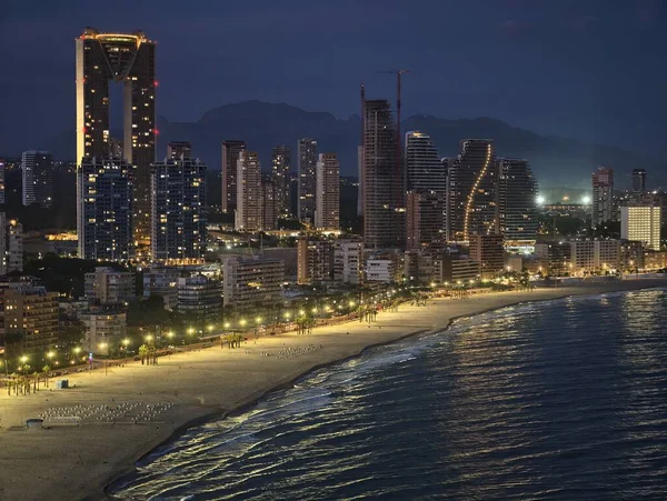 Şehir ışıklarıyla aydınlatılmış kıyı şeridi, sakin gece manzarası parlak sahil yolu.