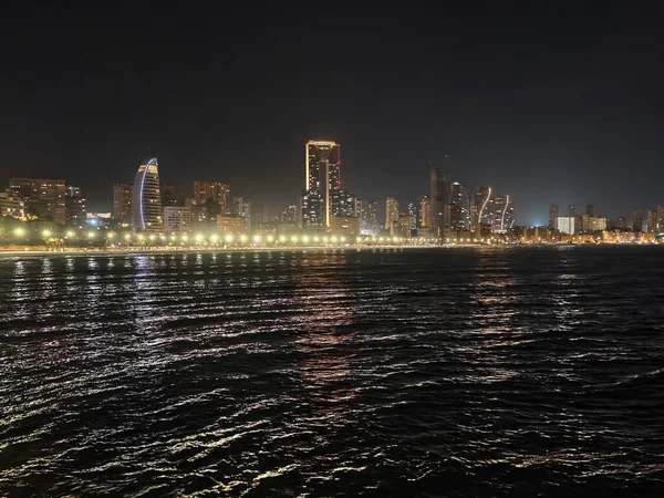 Işıl ışıl liman manzarası, hafif dalgalanmalarla, sakin kıyı silueti yumuşak, ışıl ışıl rıhtım ışıkları altında.