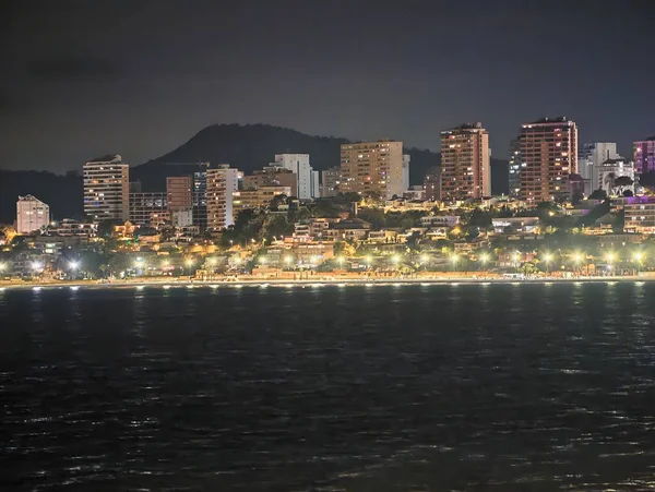 Canlı kentsel ufuk çizgisi sakin suları renkli yansımalar ve canlı atmosferle aydınlatıyor.