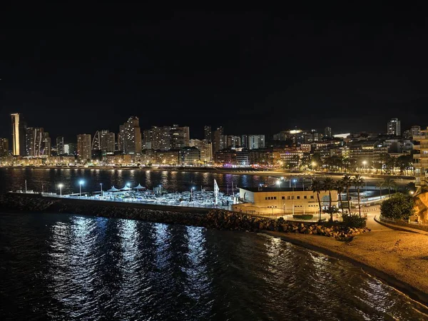 Sakin rıhtım yolu, sakin liman ve parlayan sokak ışıklarının olduğu huzurlu gece manzarası.