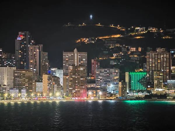 Kıyı boyunca parlak şehir ışıkları gece fotoğrafçılığı ve turizm için canlı bir atmosfer yaratır.