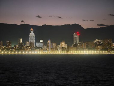 Kentsel gökyüzü yansıtıcı sularla aydınlık gökdelenlerle dolu gece şehir manzarası