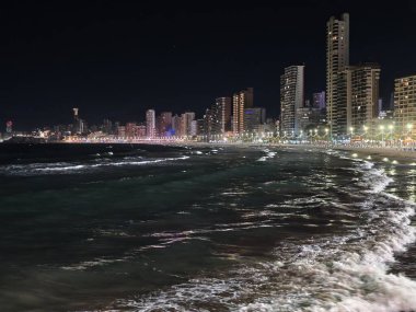 Şehir ışıkları suya yansıyor. Zarif bir sahil akşamı. Işıldayan ışıklar ve huzur dolu bir gece.