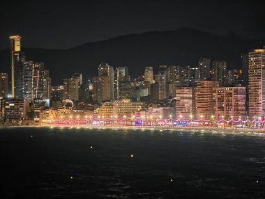 şehir ışıkları dağ siluetine karşı, gece sahnesi kıyı aydınlatması ve ufuk çizgisi