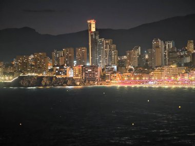 Işıklandırma sahili simgesi, aydınlatılmış yapı kuleleri gece parıldayan kıyı silueti.