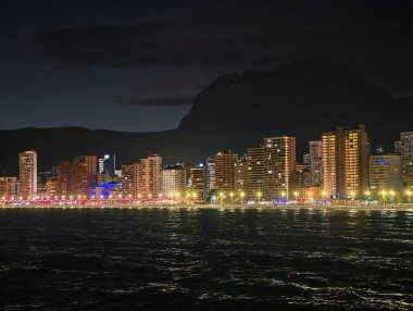 Suyun üzerinde yansımalarla renkli bir akşam yürüyüşü, canlı gece yürüyüşü ışık ve su sergileniyor.