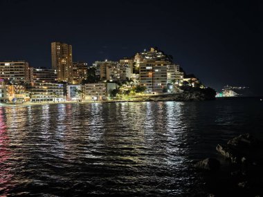 Sakin körfez, şehir binalarını ve sakin gökyüzünün altındaki suları yansıtarak aydınlandı.
