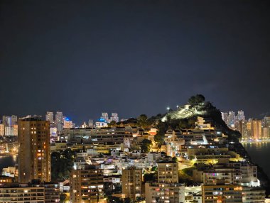 Geniş bir liman. Ufuk çizgisi aydınlık. Şehir ışıklarının suya yansıyan geniş panoramik manzarası.