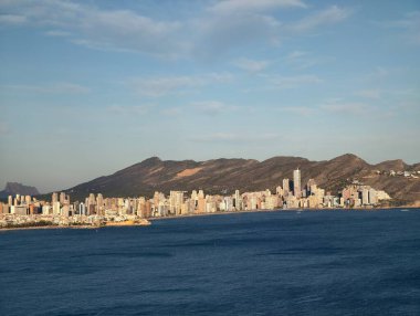 Dağın manzaralı şehir limanı, yüksek binaları ve dağ manzaralı sakin kıyı kasabası.