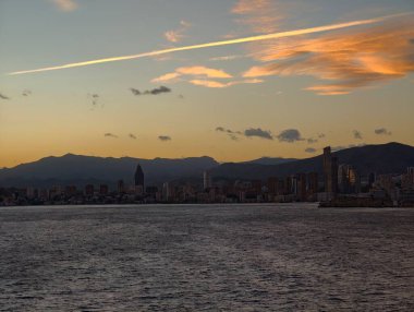 Gün batımında siluet, uzak dağ sıraları ve atmosferik katmanlarla sakin alacakaranlık sahnesi