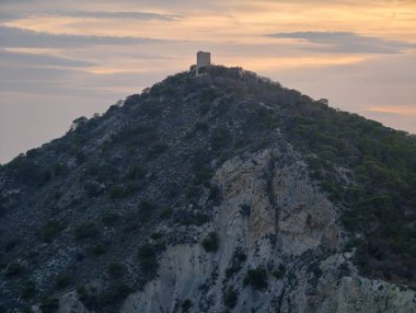 Engebeli kıyı şeritleri üzerinde altın gökyüzü, huzurlu tepe tepeleri engebeli uçurumlar ve sakin okyanuslar.
