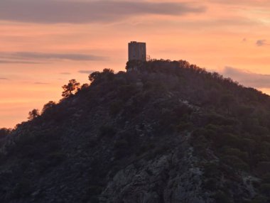 Destansı sahne, karşıt bulut oluşumlarıyla parlayan gökyüzüne karşı siluetli işaret fenerini gösteriyor.
