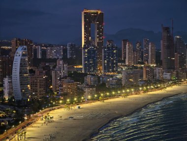 Zarif liman ışıkları sakin suları, sakin deniz manzarasını parıldayan şehir yansımalarını yansıtır.