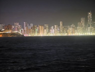 Parlak kıyı şeridi silueti, hareketli tahta kaldırımlar ve enerjik deniz eğlence alanları.