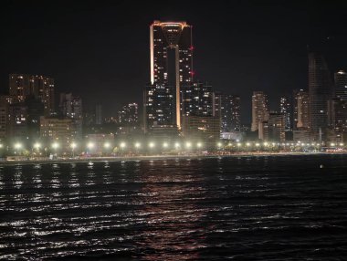 Huzurlu bir gece sahnesi yansıtıcı gökdelenler ve hafifçe parıldayan gezinti güvertesi ışıkları