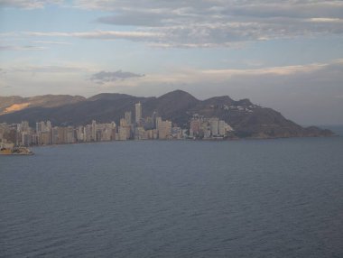 Gün batımı şehir manzarası görselleri, akşam parıltısı dağ sırasına göre belirlenmiş metropoliten kıyı şeridi.