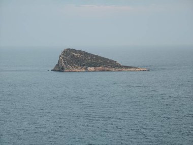 Sakin, ıssız ada manzarası, sakin okyanusun ve solgun gökyüzünün ortasında sakin, izole bir ada.