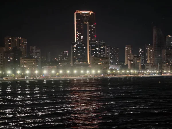 Huzurlu bir gece sahnesi yansıtıcı gökdelenler ve hafifçe parıldayan gezinti güvertesi ışıkları