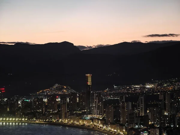 Akşam şehir ışıkları, sakin şehir manzarası alacakaranlıkta yumuşak tonlarla ve uzak dağlarla