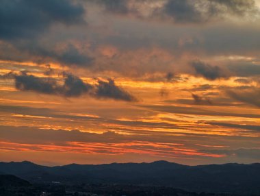 Karanlık manzaralı dağ sıralarında, huzurlu günbatımı uzak engebeli engebeli yerlerde altın renkler sergiliyor.