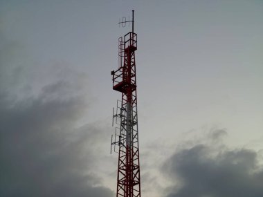 Minimalist görüntü, karamsar günbatımı bulutları ve atmosferik bulutlar arasında endüstriyel iletişim kulesini yakalıyor.