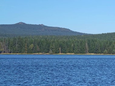 Uzak dağlarla dolu canlı bir göl manzarası, dağ hatlarıyla eşleştirilmiş sakin bir su vücudu.
