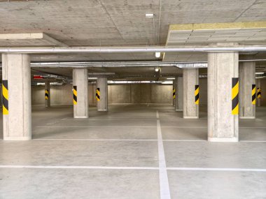 Parlak beton zemin ve sofistike ambiyansla donatılmış şık yeraltı otoparkı.