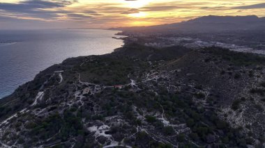 dramatik sahil manzarası, akşam parıltısı engebeli uçurumlar ve çalkantılı denizler üzerinde dramatik gölgeler oluşturur.