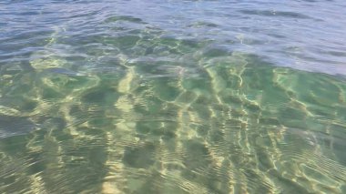 Dalgalanma efektleri olan sığ okyanus tabanı, hareket eden su ve nazik dalgalarla çakıllı güneş ışığı.