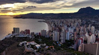 Kentsel ufuk çizgisi parıldayan okyanusla buluşur, sinematik dron şehrin ufuk çizgisini okyanus ve dağlarla yakalar