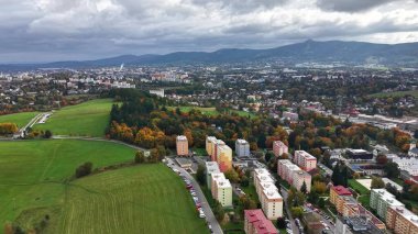 Doğa ve binalarla dolu şehir manzarası, yoğun yüksek kümeler yeşil tepeler ve uzak ufuk çizgileri arasında
