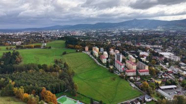 Canlı ufuk çizgisi sahnesi, yemyeşil ve uzak tepeler arasında canlı apartman dairelerinin görüntüsü.