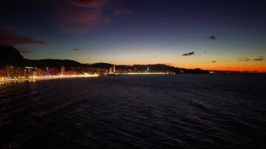 Işıl ışıl yürüyen sakin liman, limanın üzerinde alacakaranlık parlayan ışıklar ve uçan martılarla