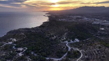 Kayalıkların ve ağaçların üzerinde sakin günbatımı, ormanlarla ve engebeli kıyı şeritleriyle sakin alacakaranlık manzarası