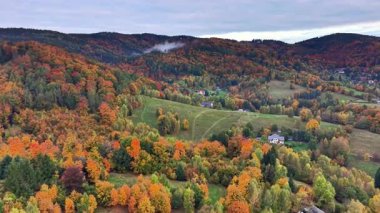 Sisli dağ manzarası, dağınık evleri olan çiğ tepeler, yuvarlanan tepelerle çevrili sisli vadi.