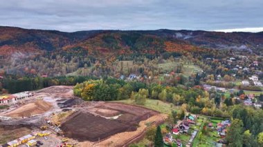 arazi temizleme sahnesi, sonbaharda orman kenarında ekipman operasyonu yakınlardaki evler ve kazılarla birlikte