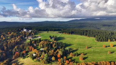 Sonbahar mezrası ve seyyar tarlalar insansız hava aracı perspektifi, kilise kulesi ve rengarenk ağaçlar.
