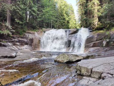 Kayalık şelale granit çıkıntının üzerinde köpüklü havuz ve desenli taş, jeolog alan çalışma titreşimi ile çağlıyor.