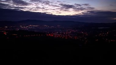 Gece şehir silueti, alacakaranlıkta dağ siluetleri üzerindeki aydınlık sokakların hava perspektifi