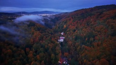 Gözlerden uzak ağaçlık patika, rahat bir kulübeye açılıyor. Etrafı canlı sonbahar yaprakları ve uzak mesafelerle çevrili.