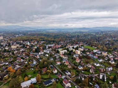 Kenar mahallelerin çatıları bulutlu gökyüzü ve kesişen yollar ve kompakt yerleşim alanlarıyla sarmalanmış.