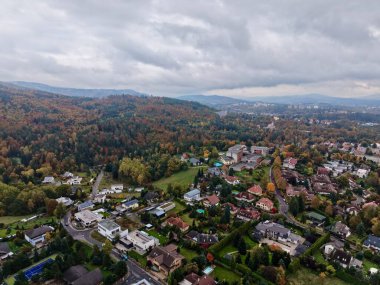 Huysuz gökyüzünün altındaki sonbahar köy merkezinde kümelenmiş evler, ağaçlık şeritler, yamalı bahçeler ve zengin bahçeler var.